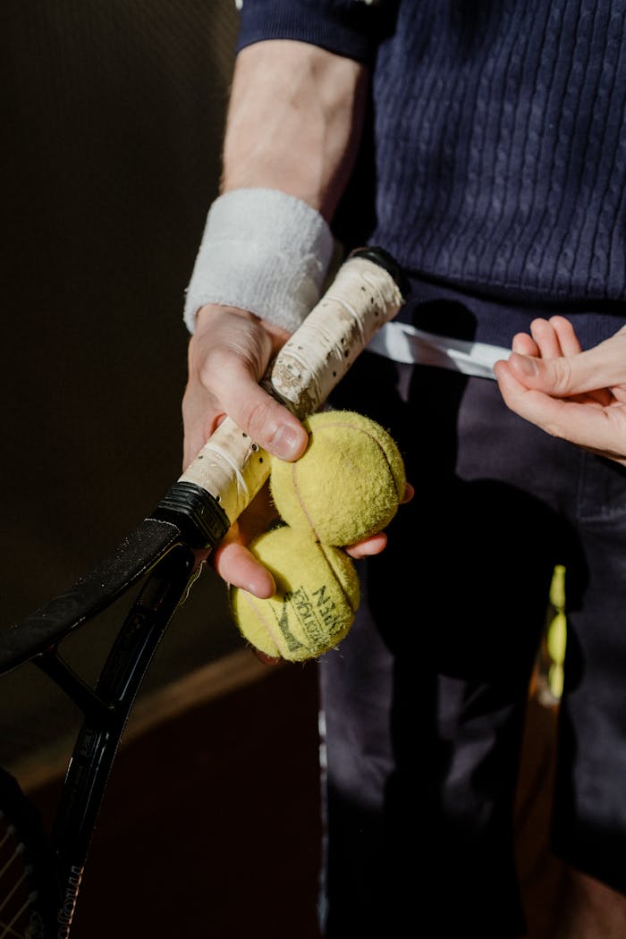 A tennis player holds balls and a racket, showcasing sports equipment in a dynamic close-up.