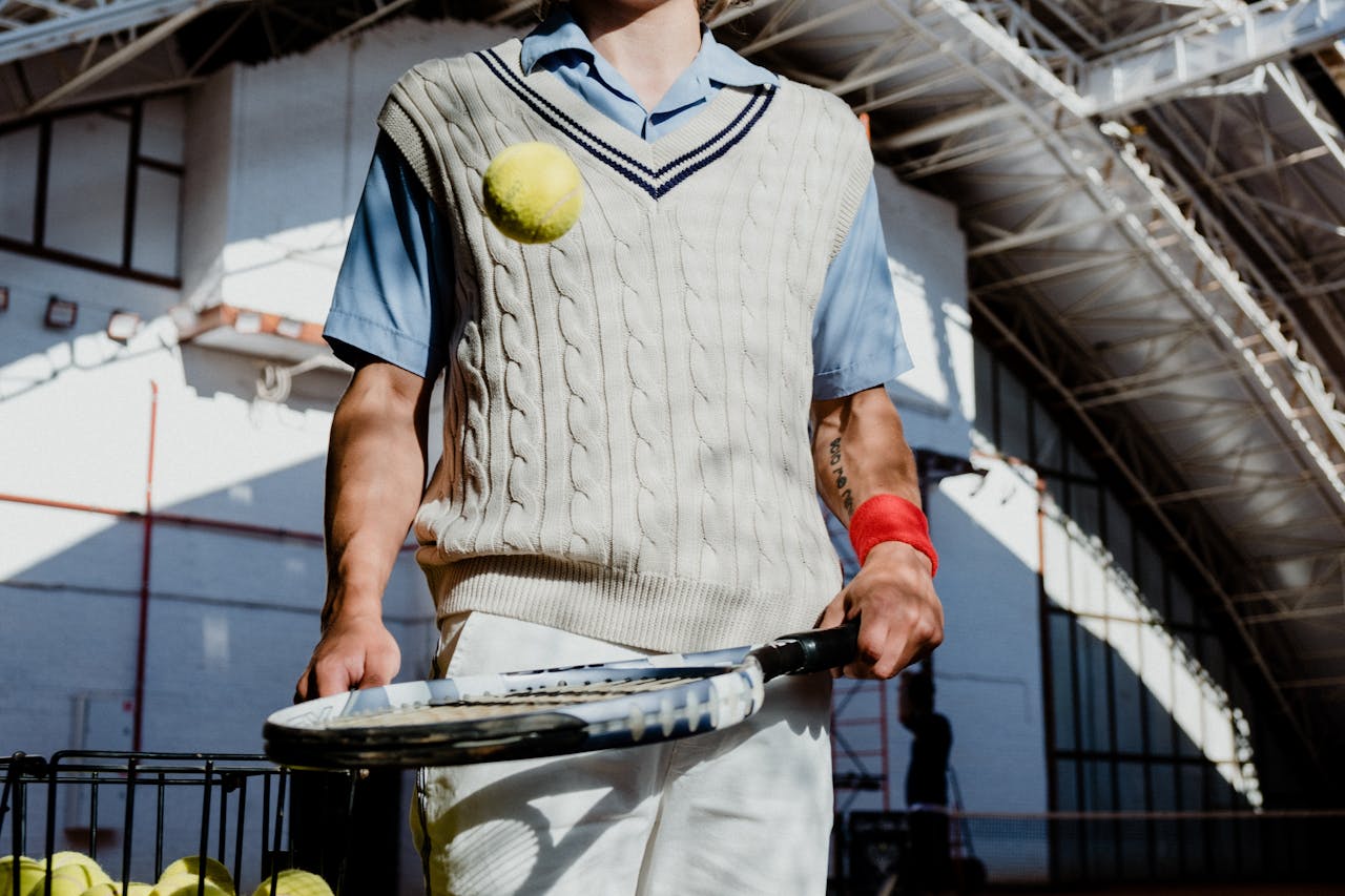 A retro-clothed tennis player in an indoor court capturing a dynamic tennis moment.