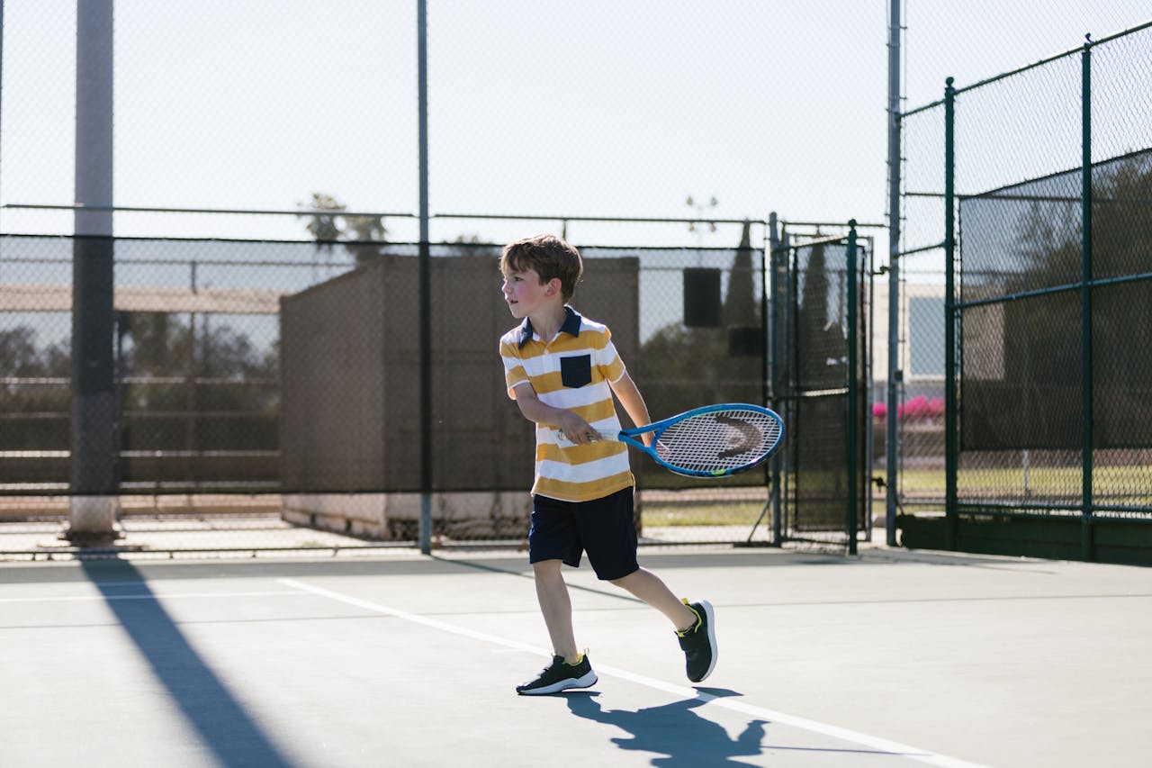 Young boy enjoying tennis practice on a bright day outdoors.